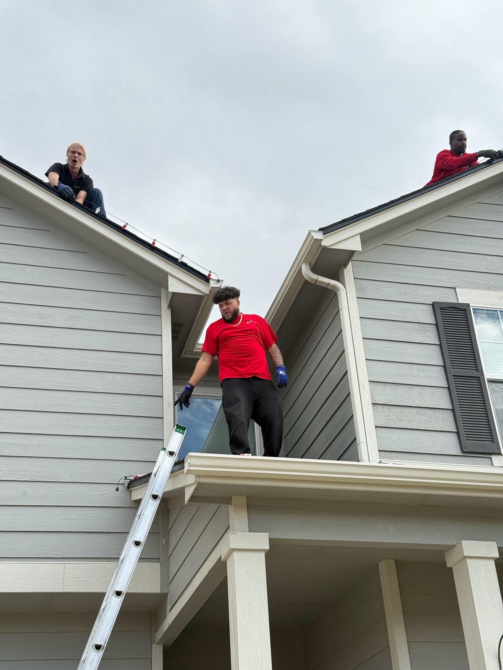 Our team installing multicolor Christmas lights along roof peaks Our team installing multicolor Christmas lights along roof peaks